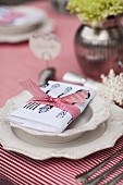 China plate with raised pattern on red and white striped tablecloth and napkin tied with ribbon