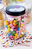 Storage jar of colourful gumballs decorated with pink ribbon