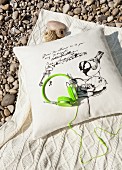 Trendy headphones in neon green on cushion and woollen blanket on gravel floor