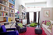 Former salesroom converted into spacious living room with colourful accessories and tall bookcases against wall
