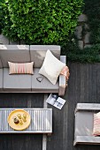 View down onto grey-upholstered outdoor furniture and coffee table on wooden terrace