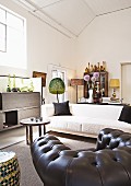 Schwarzer Ledersessel, weisses Sofa und afrikanische Kleinmöbel in grosszügigem Wohnraum