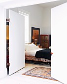 View through open double doors into bedroom with Oriental-style bed and wardrobe