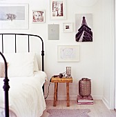 Vintage-style metal table next to rustic bedside table below photos and drawings on wall