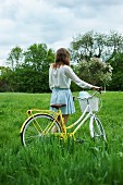 Girl with bicycle in green meadow