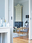 Collection of vases on console table in anteroom next to open sliding door; armchair and tiled stove in corner of room beyond