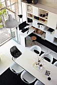 Blick von oben auf weissen Esstisch und moderne Stühle, gegenüber Regalschrank und integriertem Schreibplatz