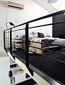View of DIY bed on black rug in sleeping area seen through black metal balustrade