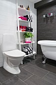 Bathroom with towels on ladder shelves, white clawfoot bathtub and charcoal tiles