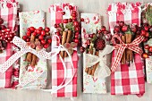 Hand-crafted, gingham and floral napkins decorated for Christmas with ribbons, berries and cinnamon sticks