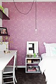 Bedroom with bed, bedside table & desk in front of wall with purple patterned wallpaper