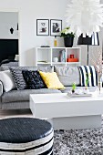 White coffee table in front of grey sofa with colourful scatter cushions in modern living room