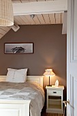 White double bed in wood-panelled attic bedroom