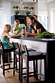 Young family around counter with bar stools in open-plan kitchen
