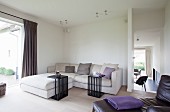 Beistelltische aus schwarzen Holzlamellen vor heller Couchkombination in minimalistischer Wohnzimmerecke