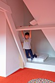 Junge in ausgebautem Dachzimmer beim Turnen an weißer Holzkonstruktion