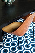 Retro Stuhl mit Holzschale vor dunklem Eichentisch, Retro Teppich mit geometrischem Muster