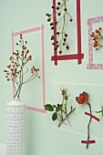 Picture frames made from washi tape around sprigs of rose hips on wall