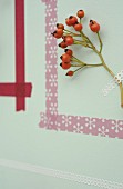 Picture frame made from washi tape around sprig of rose hips on wall