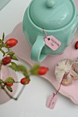 Turquoise teapot of rose hip tea and sprig of rose hips in vintage ambiance