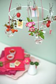 Sprigs of rose hips and delicate wild roses in tiny glass bottles hanging from white metal wreath