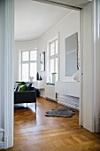 Period apartment with open double doors and animal-skin rug on parquet floor in interior with modern furniture