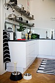 Detail of kitchen counter with white base units and animal feeding bowls on parquet floor