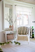 White fur blanket on wicker chair and console table below framed mirror in rustic living room