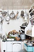 Pots and pans hanging from rod over cooker with kitchen utensils