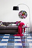 Self-adhesive vinyl tiles as new look in living room combined with hot pink blanket and floral scatter cushions on grey leather sofa