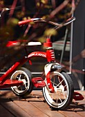 Red and white, vintage-style child's tricycle on wooden terrace