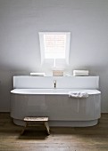 Bathtub by Philippe Starck with antique bronze tap in minimalist bathroom under skylight