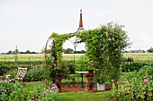 Romantic seating area under climbing roses on delicate metal pavilion in rural setting