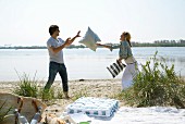 Couple on a beach picnic throwing cushions