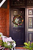 Wreath of flowers on dark grey front door with stained glass windows