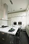 Kitchen island with marble worksurface in white fitted kitchen with black floor tiles