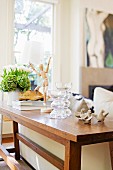 Artists’ mannequin, glass goblets and bird ornaments arranged on console table against back of sofa