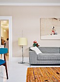 Partially visible sofa, photo on pastel wall and standard lamp in living room