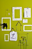 Stems of lavender in wire and paper picture frames on green wall