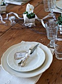 White place setting with glasses and violas on rustic wooden table