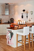 Upholstered bar stools at counter in open-plan, country-house kitchen