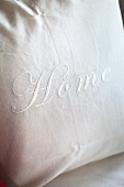White cushion cover embroidered with lettering