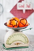 Oranges stuck with cloves in star and heart-shaped motifs on retro kitchen scales
