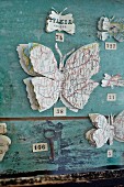 Selbstgebastelte Schmetterlinge aus Landkarten, an verwitterter Wand