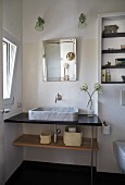 Modern washstand with marble countertop basin below mirror and two sconce lamps in corner of bathroom