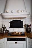 Country-house-style fitted kitchen with masonry extractor hood above ceramic hob