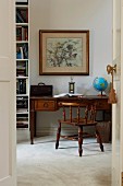 Illuminated globe on Art-Nouveau desk, armchair with turned spindles and full bookcase