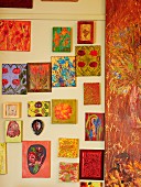 Farbenfrohe Bildersammlung mit gemalten Blumenmotiven an hellgelber Wand