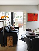Vintage standard lamp with small yellow lampshades next to black sofa and ethnic, wooden coffee table in modern interior