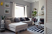 Small side tables on black and white striped rug and sofa combination in interior with walls painted pastel grey